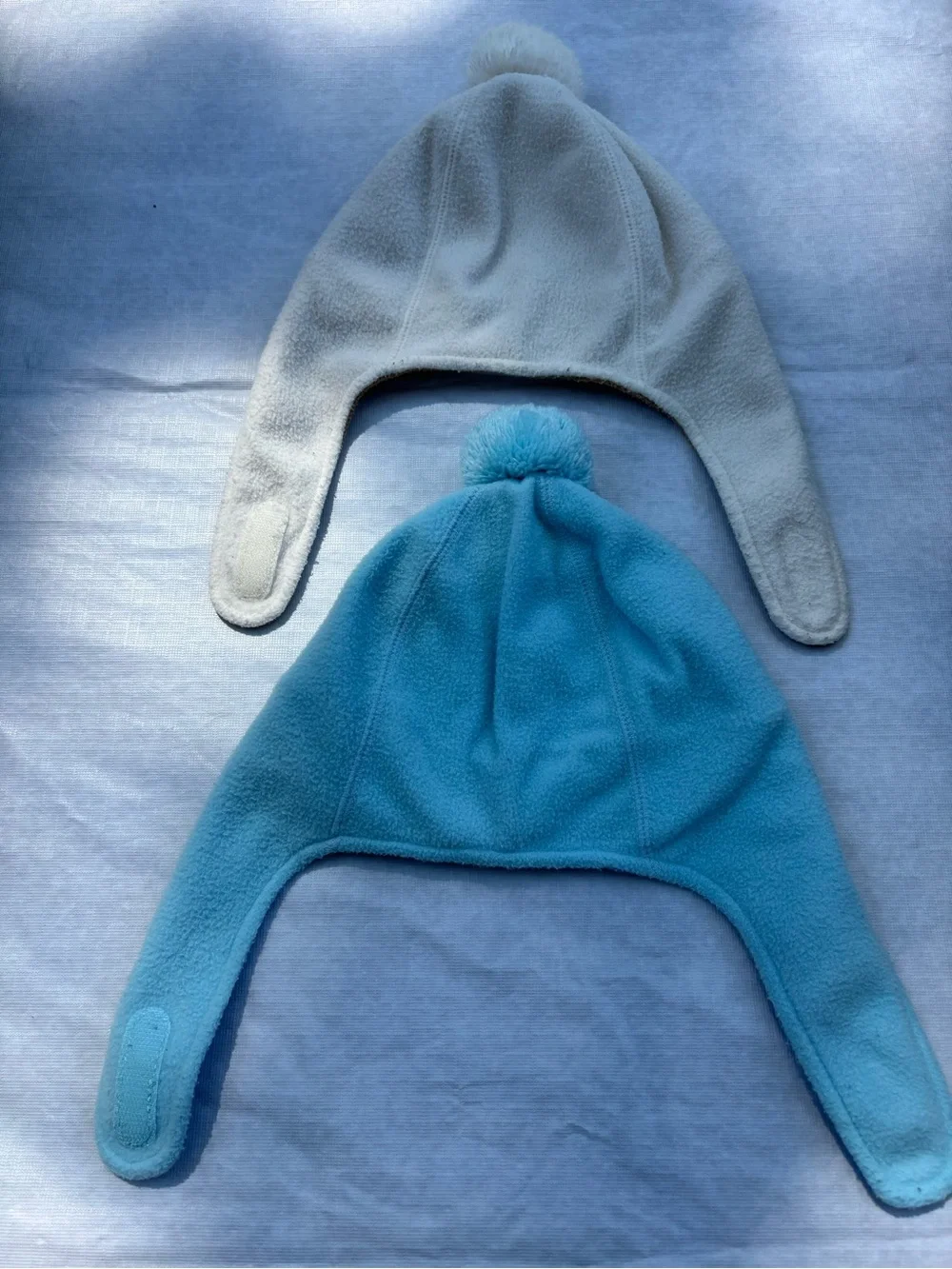 The North Face Fleece Earflap Pom-Pom Hats in Cream & Light Blue